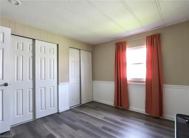 Unfurnished bedroom featuring a textured ceiling, wood-type flooring, and two closets