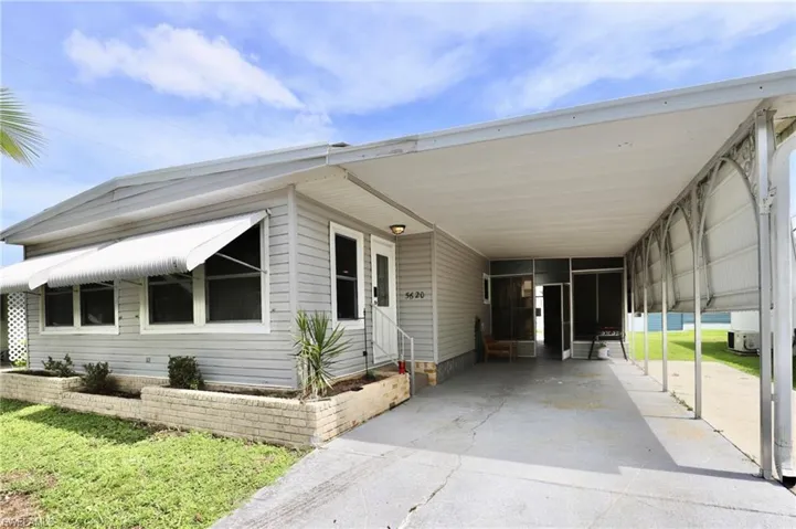 View of front of home with a carport and a front yard