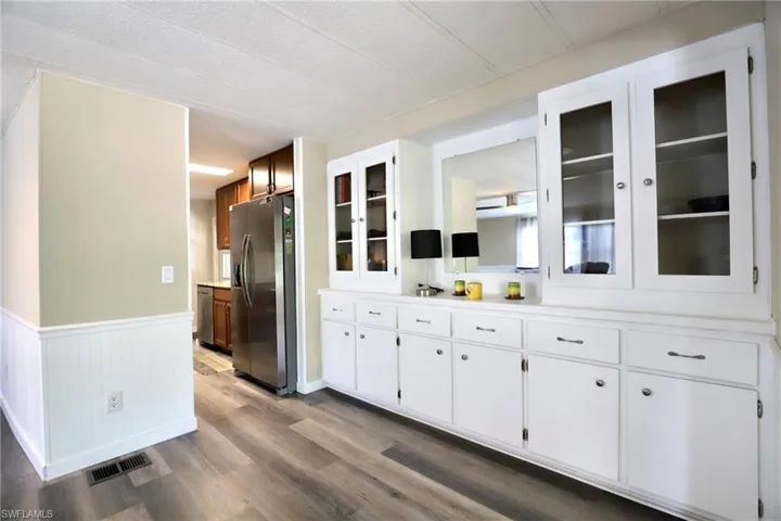 Kitchen with stainless steel refrigerator with ice dispenser, white cabinetry, and hardwood / wood-style floors