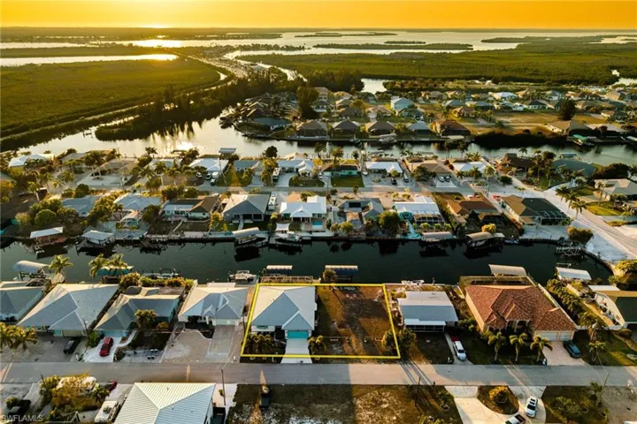 Aerial view of residential area with property parcel outlined and a large body of water