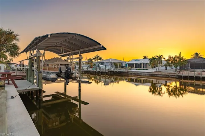 Dock featuring boat lift, a water view, and a residential view