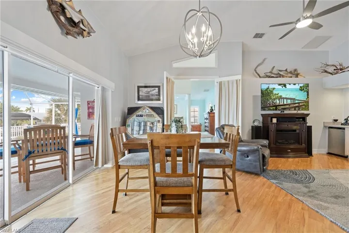Dining space with light wood finished floors, a ceiling fan, vaulted ceiling, and a chandelier