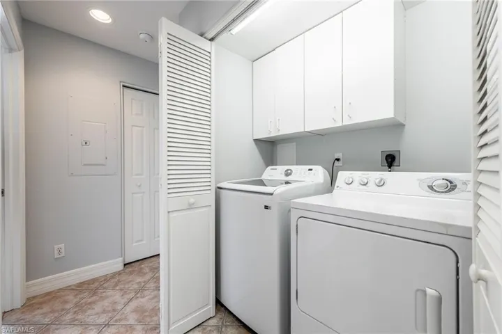 Laundry area with cabinet space, light tile patterned flooring, and recessed lighting