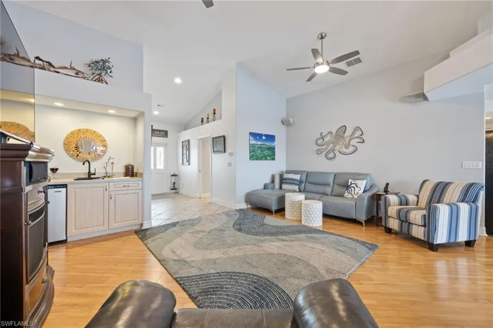 Living room featuring ceiling fan, light wood finished floors, and lofted ceiling