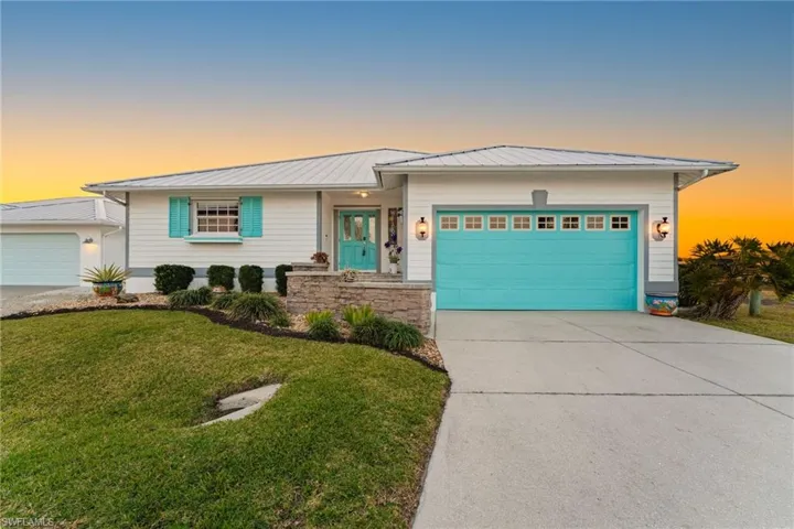 View of front of property with an attached garage, concrete driveway, a metal roof, and a front yard