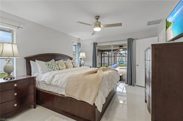 Bright room featuring white tile flooring, a ceiling fan, and sliding glass doors leading to a screened lanai with a pool