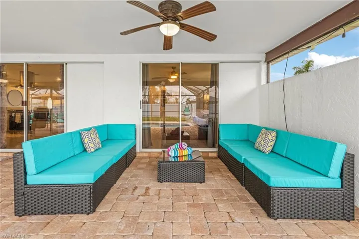 Covered outdoor patio featuring paver flooring, a ceiling fan with integrated lighting, and multiple sliding glass doors