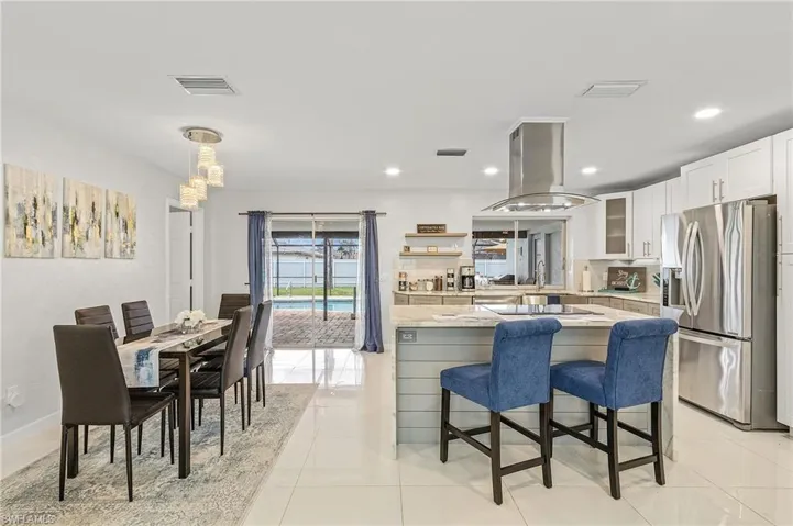 Open-concept living space featuring a modern kitchen with a stainless steel range hood, built-in cooktop, and large stainless steel refrigerator