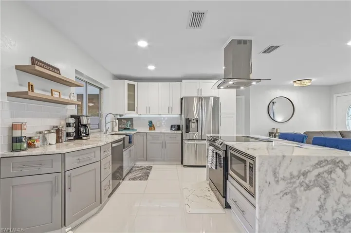 Contemporary kitchen featuring two-tone cabinetry, stainless steel appliances, and a central island with a built-in microwave