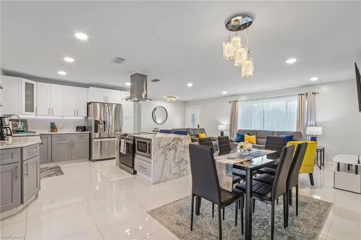 Spacious open-concept living area featuring a modern kitchen with two-tone cabinetry and stainless steel appliances, a large waterfall island with integrated microwave, and recessed lighting throughout