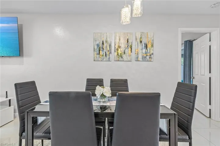 Dining area featuring light-toned walls, a contemporary chandelier, and tiled flooring