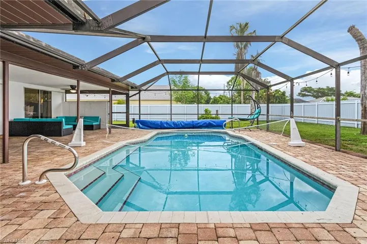 Screened-in pool area featuring a rectangular pool with integrated steps and a stainless steel handrail