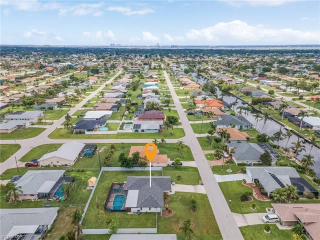 Aerial perspective showcasing a residential area with numerous single-story homes, many featuring private pools and screened enclosures