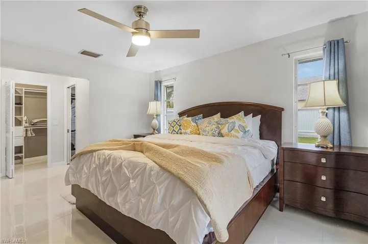 Bedroom featuring bright white walls, large format tile flooring, and a ceiling fan with integrated lighting