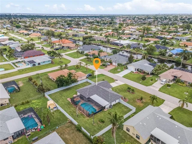 Aerial overview showcasing a property with a screened swimming pool and white perimeter fencing
