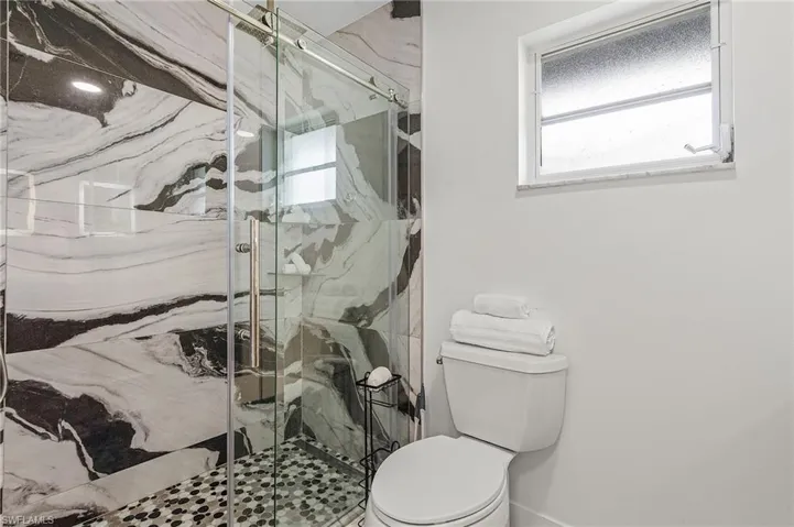 Contemporary shower enclosure featuring a sliding glass door and black and white patterned wall tile