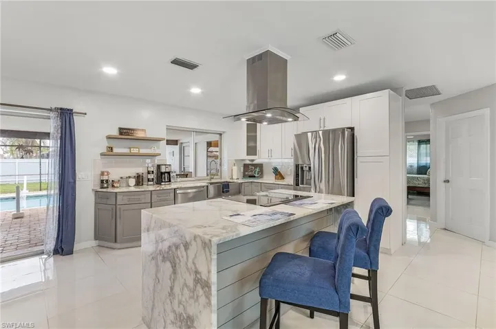 Kitchen featuring a waterfall-edge island with seating, stainless steel appliances, and two-tone cabinetry