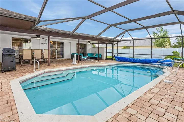 Screened pool enclosure featuring a pool with integrated steps, paver patio, covered patio space, and ceiling fans