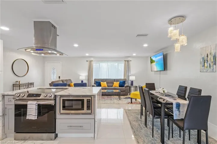 Open-concept interior featuring a kitchen island with stone countertops, a stainless steel range, and a built-in microwave