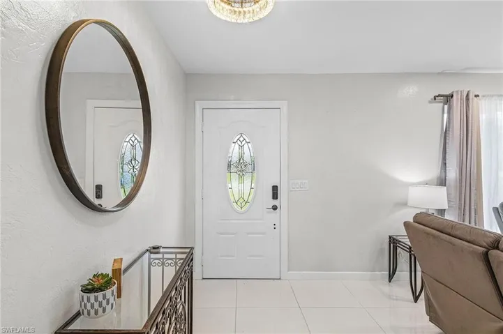 Entryway featuring white tile flooring, a decorative front door with an oval glass insert, and a ceiling-mounted light fixture