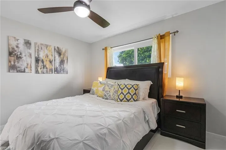 Bedroom featuring a ceiling fan, window with curtains, and light-toned walls