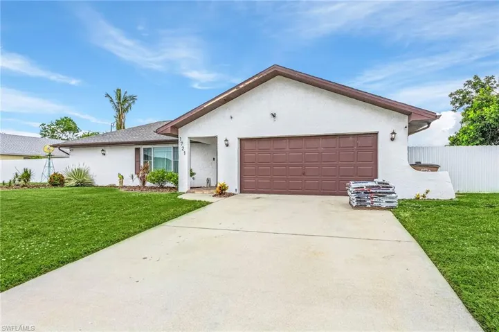 White stucco exterior featuring a brown garage door, paved driveway, and established front lawn