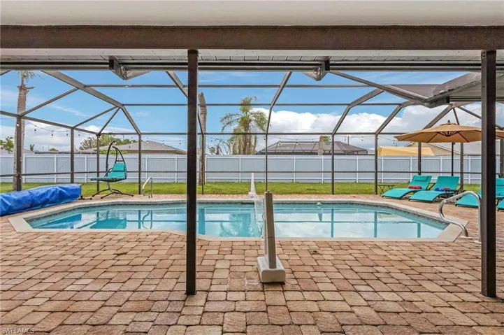 Screened pool enclosure featuring a rectangular pool with integrated steps and a surrounding paver deck