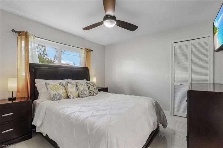 Bedroom featuring light gray walls, a window with horizontal panes, and white louvered bifold closet doors