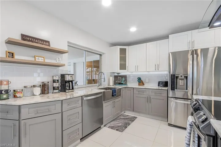 Kitchen featuring white upper cabinetry, grey lower cabinetry, stainless steel appliances, and light-colored countertops