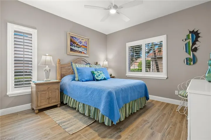 Bedroom featuring ceiling fan, multiple windows, and light wood-type flooring