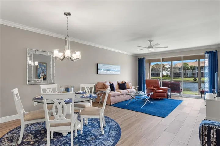 Dining space featuring light hardwood / wood-style flooring, ornamental molding, and ceiling fan with notable chandelier