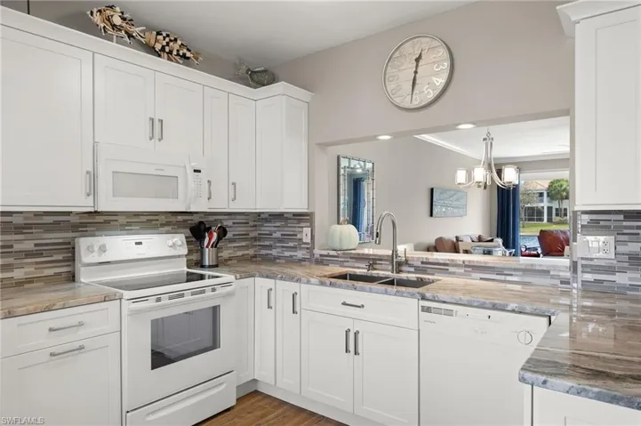 Kitchen featuring light hardwood / wood-style floors, sink, white cabinetry, white appliances, and tasteful backsplash
