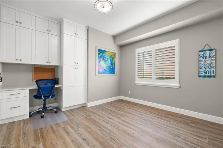 Unfurnished office featuring built in desk and light hardwood / wood-style floors