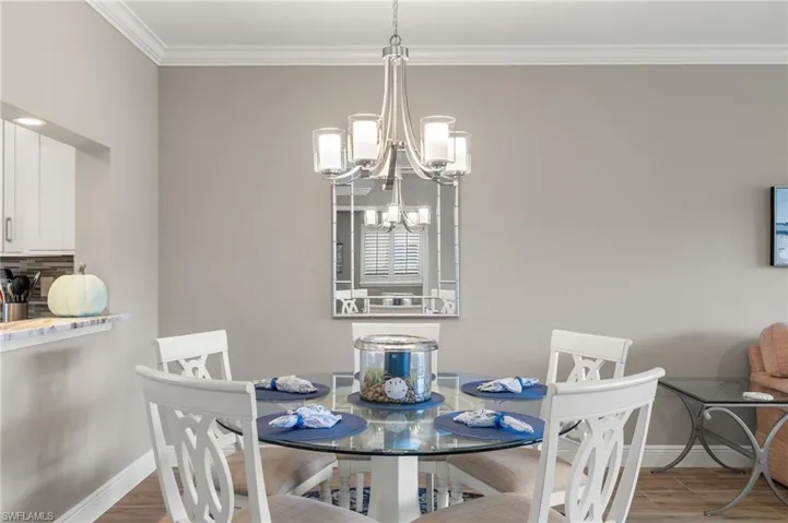 Dining room featuring wood-type flooring, ornamental molding, and a chandelier