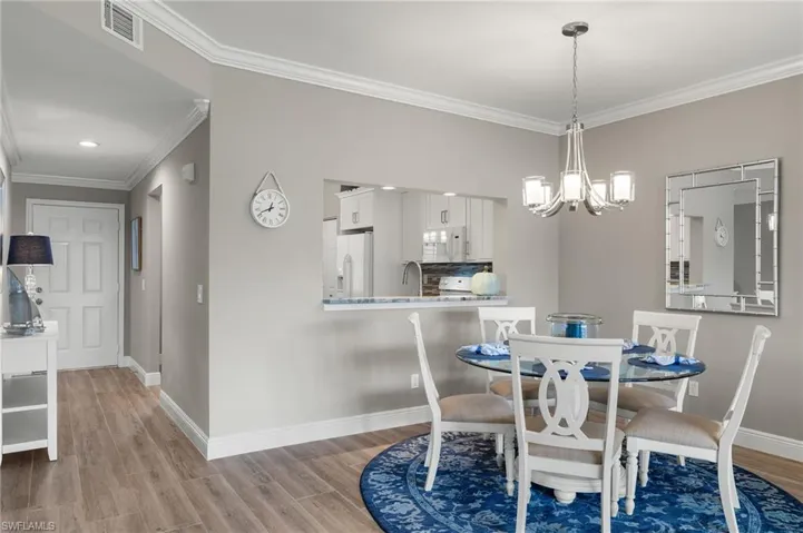 Dining area featuring a chandelier, sink, crown molding, and light wood-type flooring