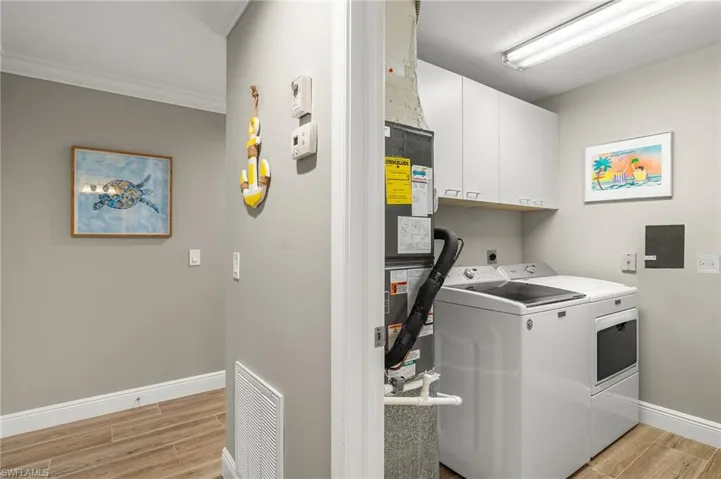 Laundry area featuring cabinets, crown molding, washer and clothes dryer, and light wood-type flooring