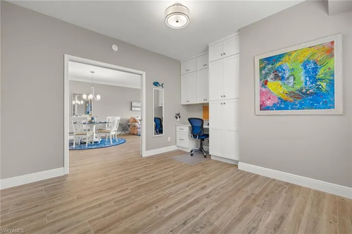 Unfurnished office with built in desk, ornamental molding, a chandelier, and light wood-type flooring
