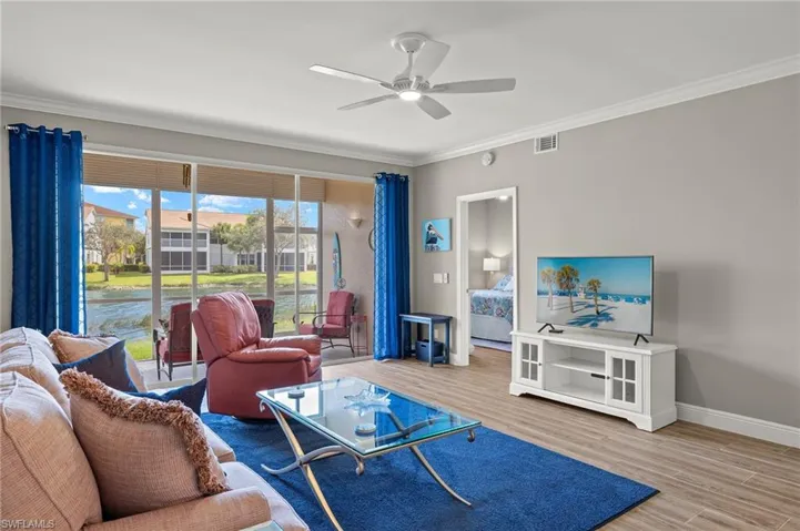 Living room with ornamental molding, hardwood / wood-style floors, and ceiling fan