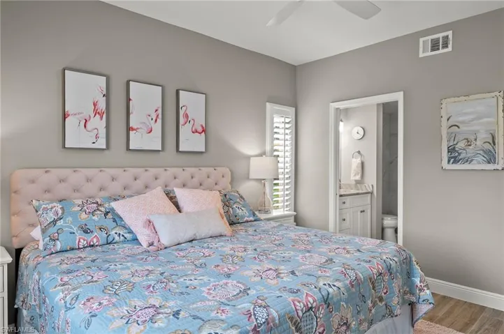 Bedroom featuring ceiling fan, light hardwood / wood-style flooring, and ensuite bath