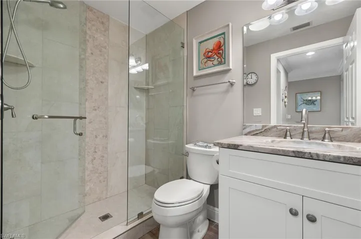 Bathroom with hardwood / wood-style flooring, toilet, a shower with shower door, vanity, and crown molding