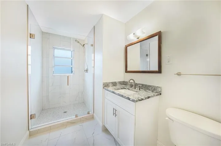 Bathroom featuring vanity, a shower with door, and toilet