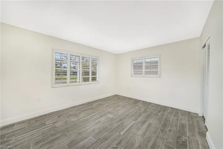 Unfurnished room with dark wood-type flooring and a wealth of natural light
