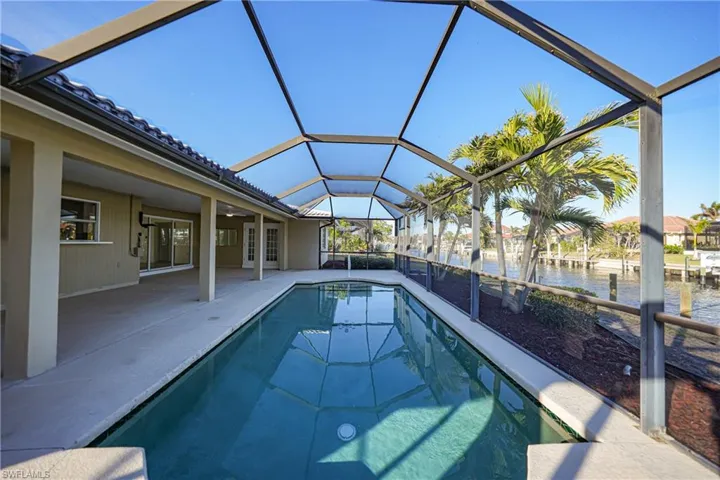 View of swimming pool with a water view, a patio area, and a lanai