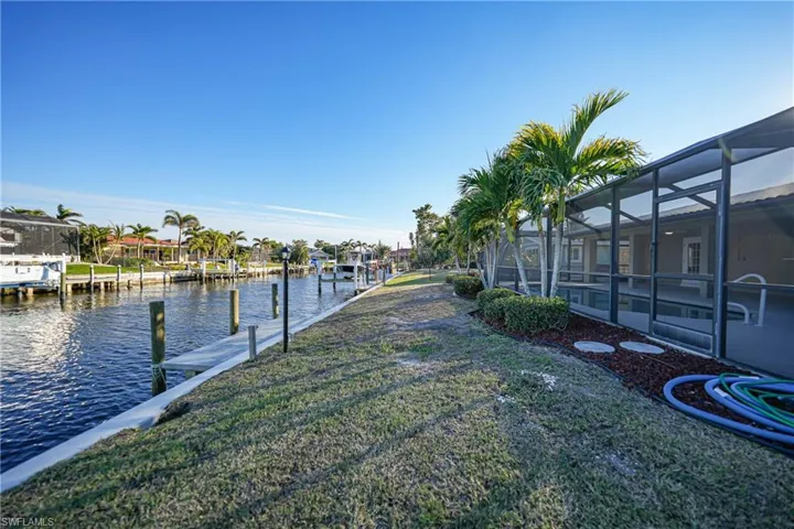 Dock area featuring a lanai, a lawn, and a water view