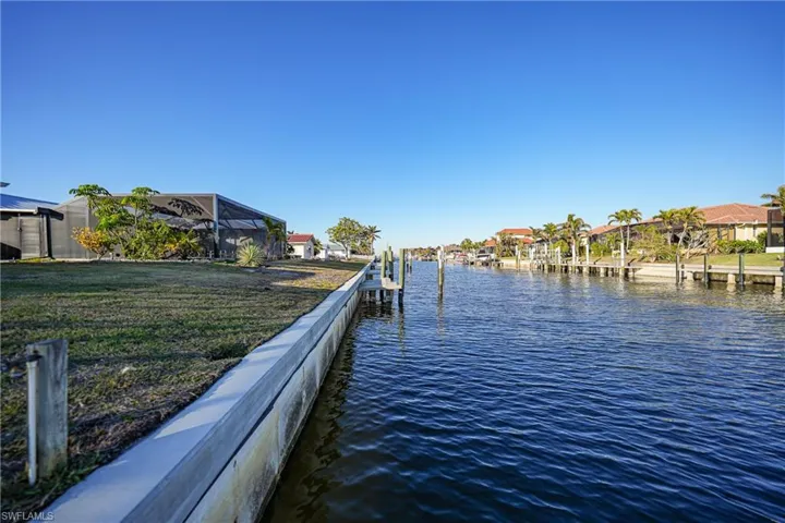 Dock area featuring a water view, glass enclosure, and a lawn