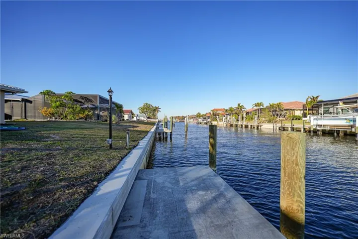 View of dock with a lawn and a water view