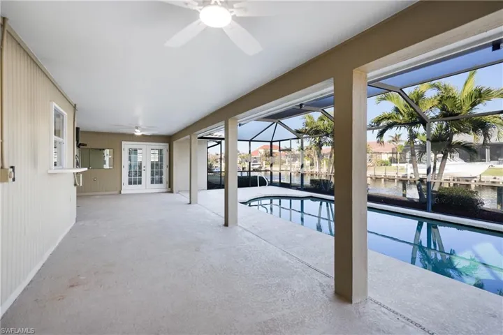 View of swimming pool with a patio, a lanai, ceiling fan, a water view, and french doors
