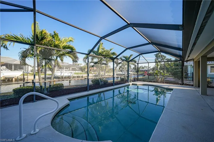 View of pool featuring a patio area and glass enclosure