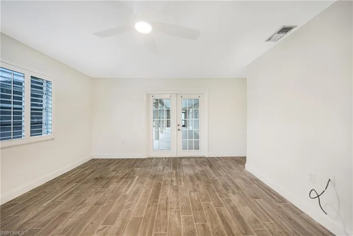 Empty room featuring hardwood / wood-style floors, french doors, and ceiling fan