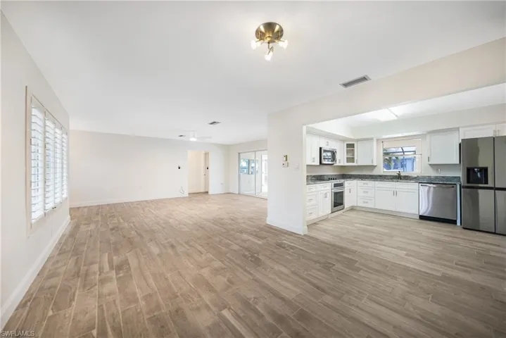 Kitchen with stainless steel appliances, sink, white cabinets, and light wood-type flooring